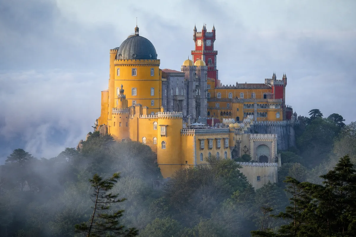 Façades colorées du palais de Pena émergeant de la brume à Sintra